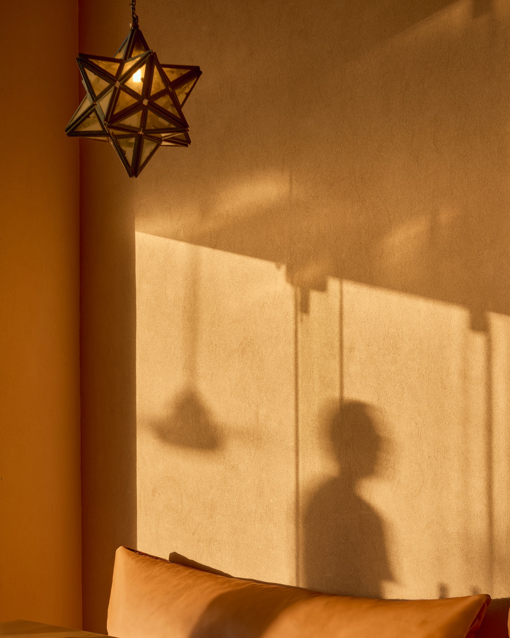 Star-shaped pendant lamp casting shadows on a warm plaster wall